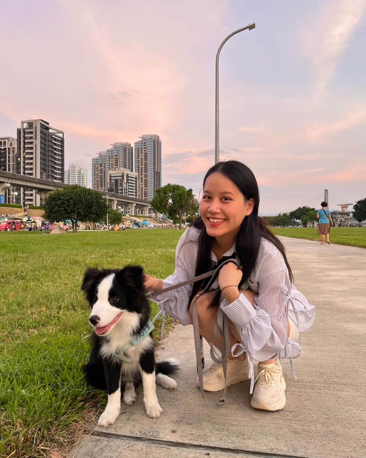 Nuts 與飼主在城市公園合照，背景是夕陽與高樓